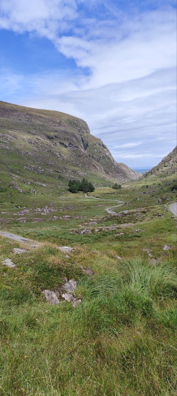 La carretera del Gap of Dunloe descendiendo entre laderas rocosas hacia el lago del fondo del valle
