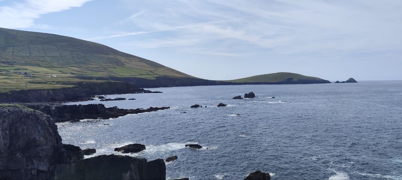 Costa rocosa y verde de Slea Head en la península de Dingle, con olas rompiendo contra las rocas