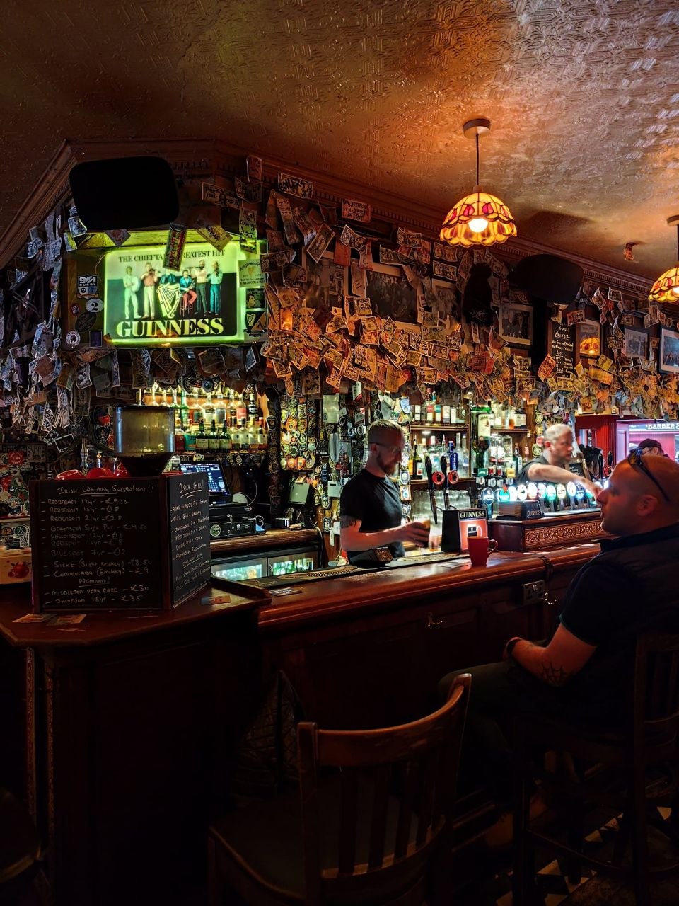 Interior de un pub irlandés en Galway, con barra de madera, cartel de Guinness y paredes llenas de billetes
