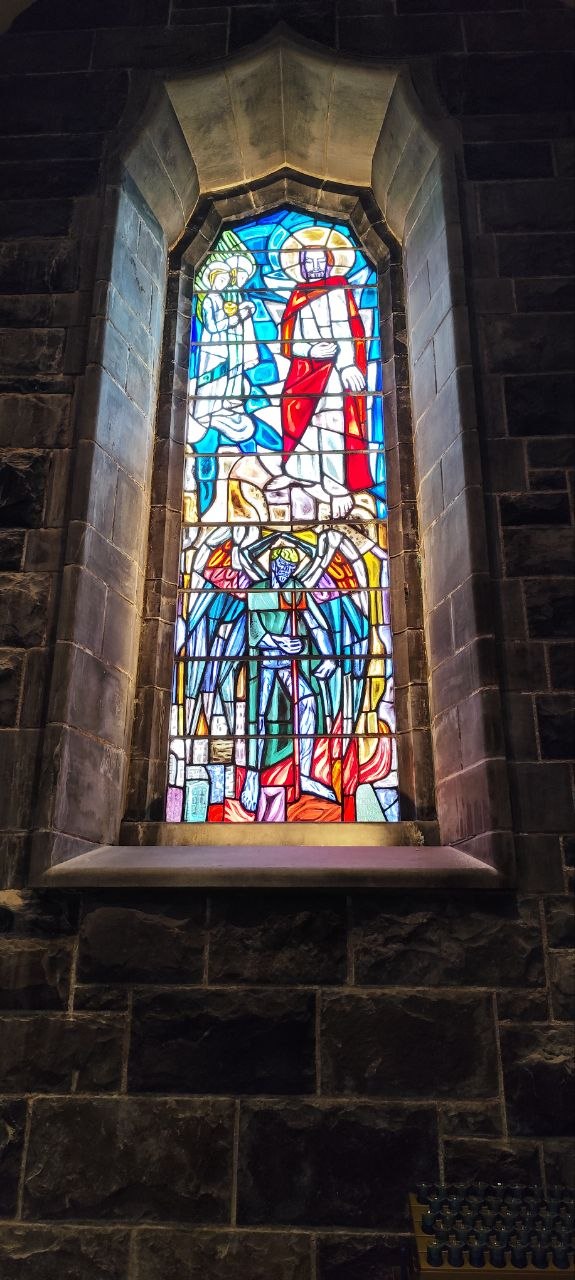 Vidriera de colores de una iglesia de piedra en Galway, con figuras religiosas